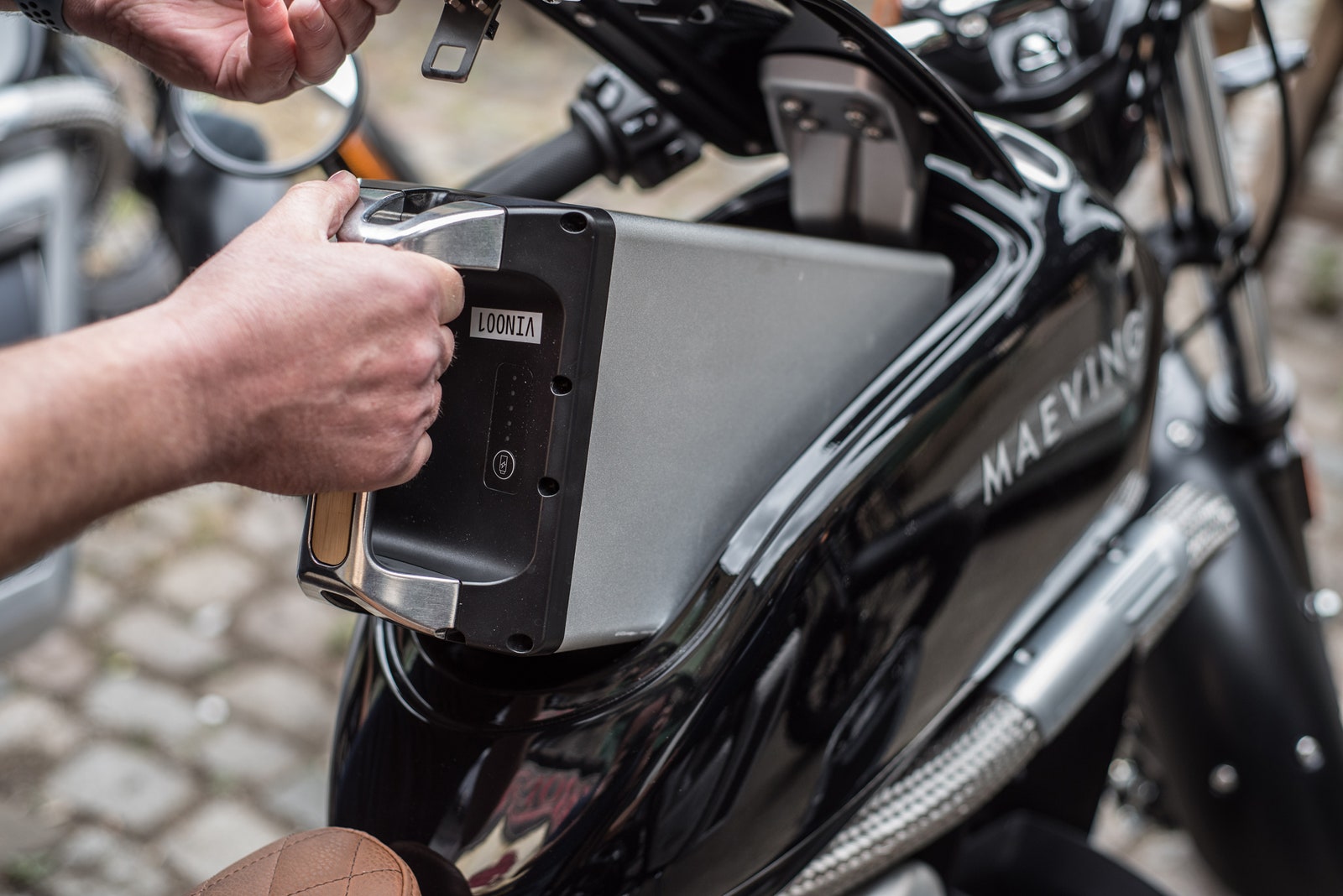 Person pulling removable battery out of Maeving RM1 electric motorcycle